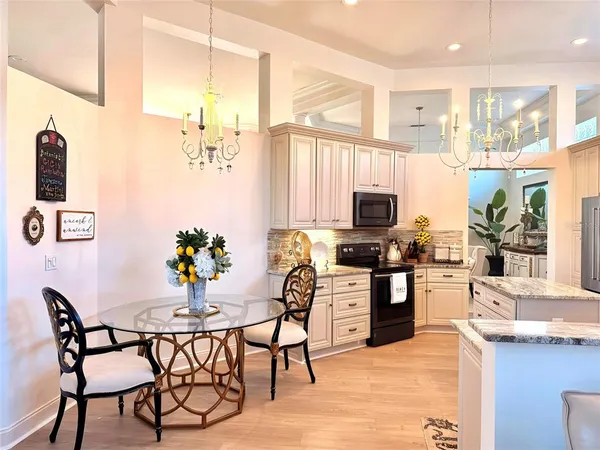 a kitchen with stainless steel appliances kitchen island granite countertop a stove top oven a sink a dining table and chairs with wooden floor