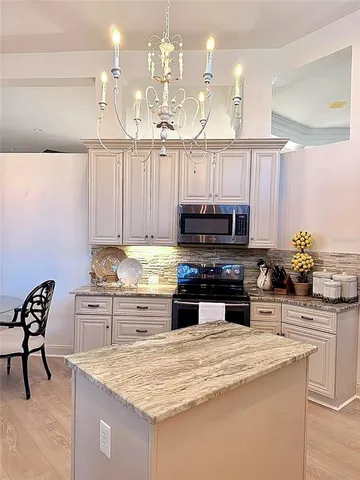 a kitchen with kitchen island granite countertop a sink a stove and cabinets