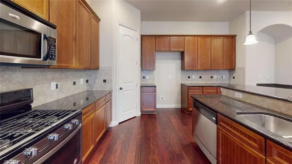 a kitchen with stainless steel appliances granite countertop a stove a sink dishwasher and a microwave oven with wooden floor