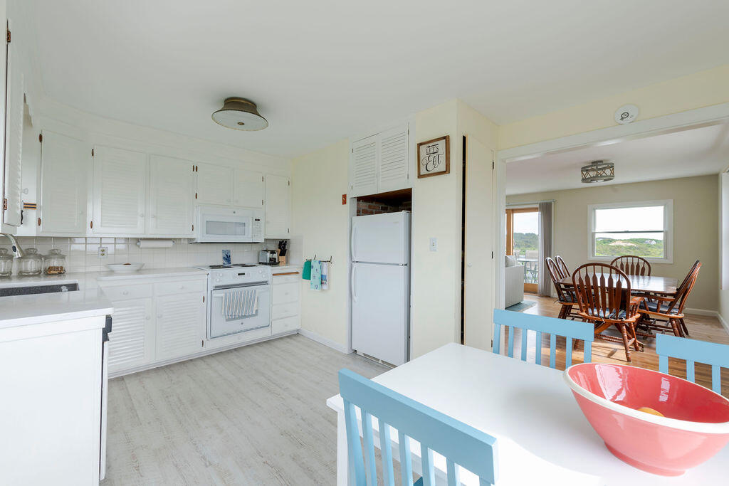 2 Ryder Hollow Road Truro, MA 02666 - Photo 15 of 33 a kitchen with a refrigerator a stove a dining table and chairs with wooden floor