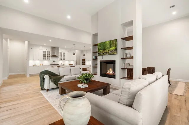 a living room with furniture a fireplace and a dining table with wooden floor