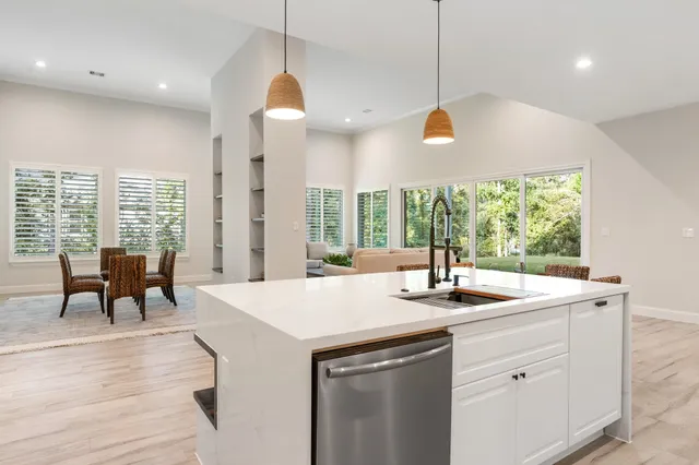 a kitchen with stainless steel appliances kitchen island granite countertop a dining table chairs and white cabinets