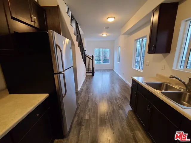 a kitchen with sink a refrigerator and wooden floor