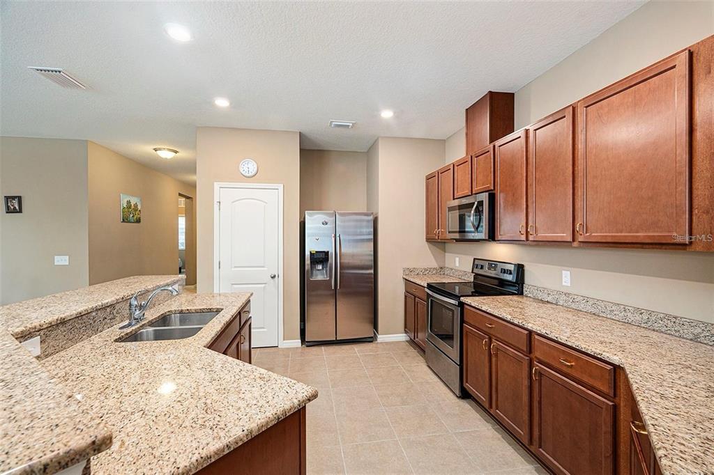 12343 Moss Lake Loop New Port Richey, FL 34655 - Photo 11 of 24 a kitchen with stainless steel appliances granite countertop a sink refrigerator and cabinets
