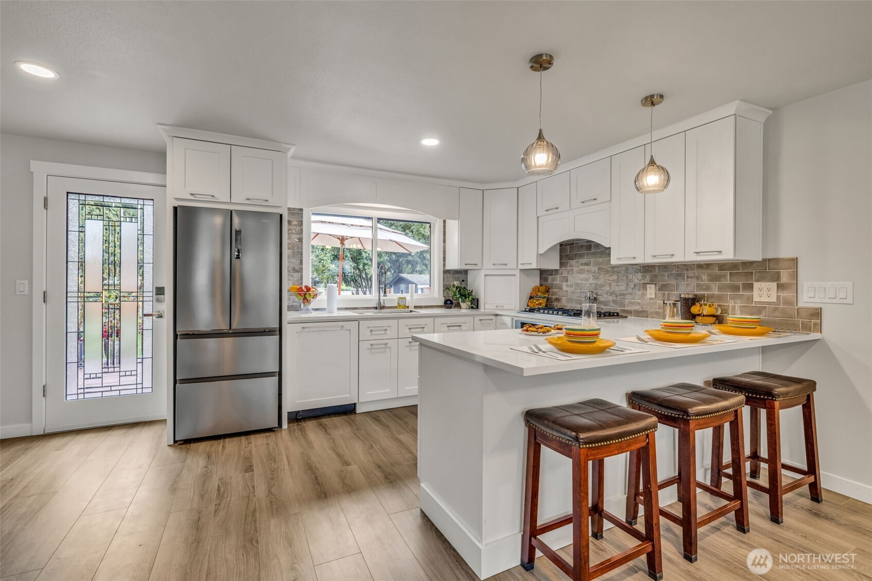 616 212th Street Southwest Bothell, WA 98021 - Photo 15 of 28 a kitchen with kitchen island a stove a refrigerator and a dining table with wooden floor