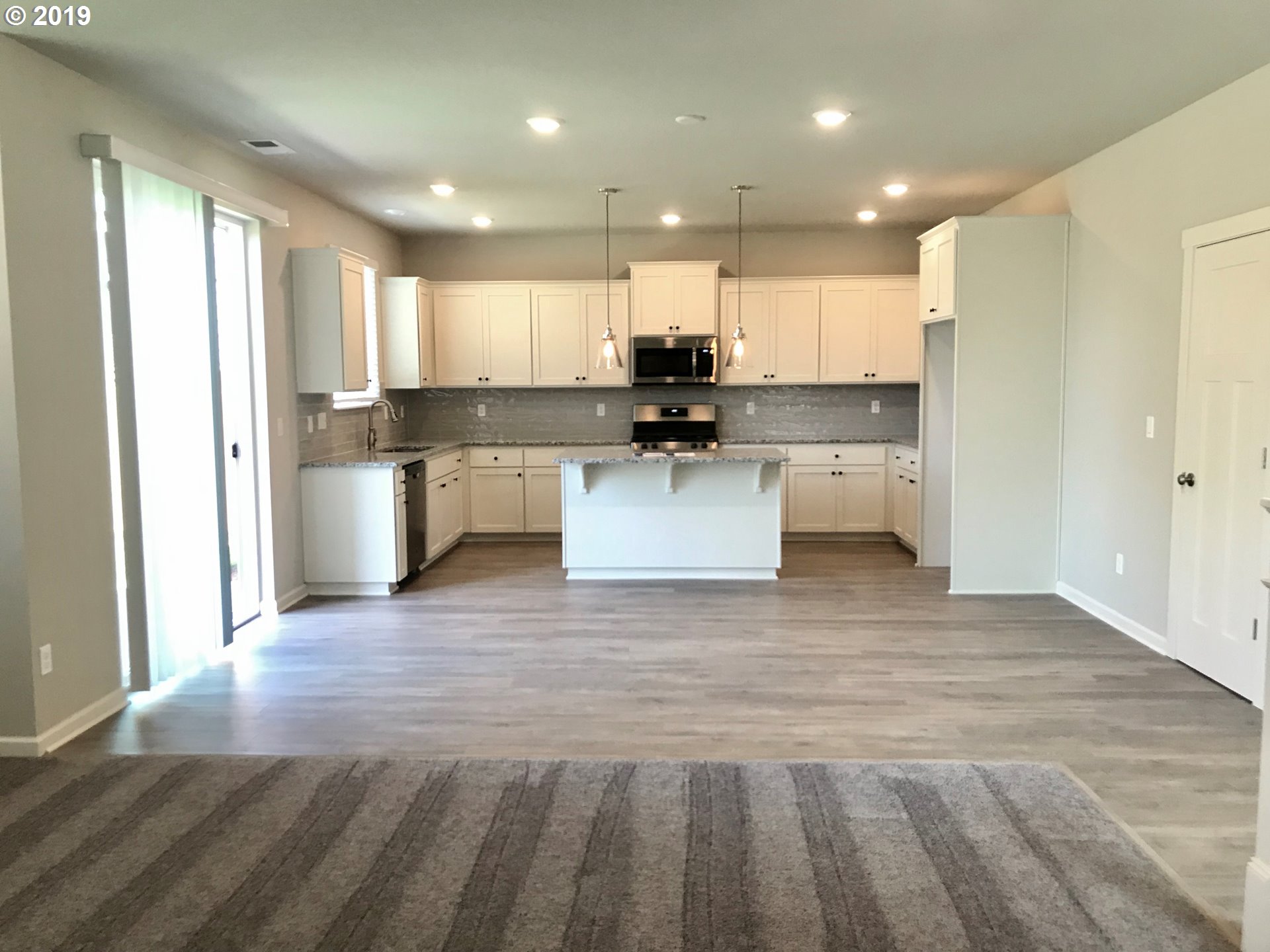 4099 Southwest Rodlun Road Gresham, OR 97080 - Photo 16 of 30 a view of kitchen with kitchen island a sink wooden floor and a counter top space