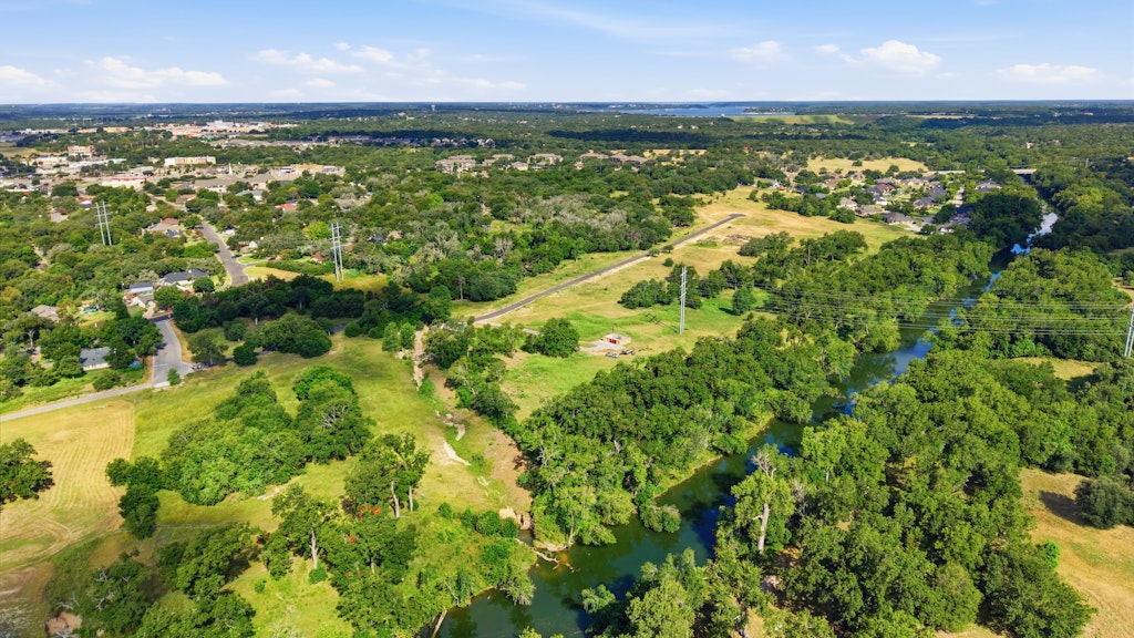 Tbd Tbd Belton, TX 76513 - Photo 9 of 16 Lush green trees line the winding river under a clear blue sky.