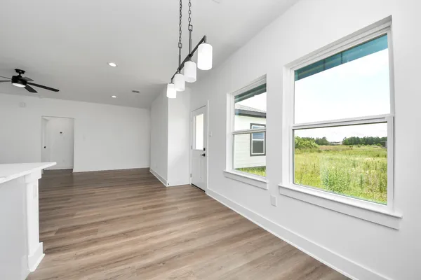 a view of an empty room with a window and wooden floor