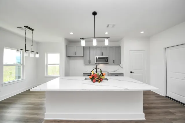 a kitchen view with living room and windows