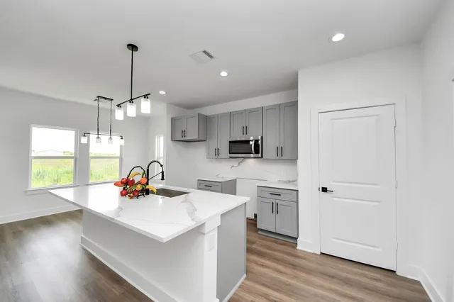 a view of a kitchen with kitchen island a sink wooden floor and a living room view