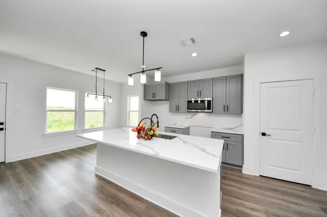 a view of a kitchen with kitchen island a sink wooden floor and a large window