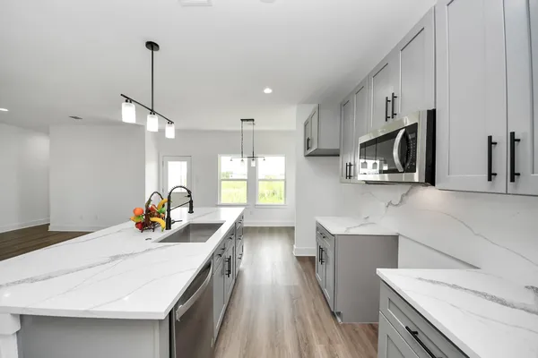 a kitchen with stainless steel appliances kitchen island granite countertop a sink a stove and a wooden floors