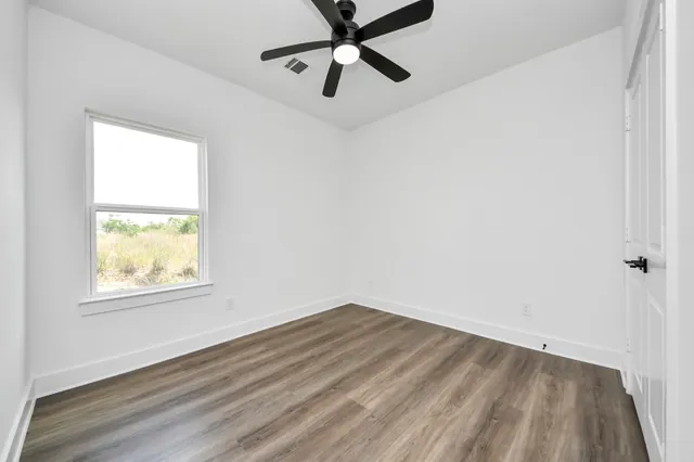 an empty room with a window and a ceiling fan