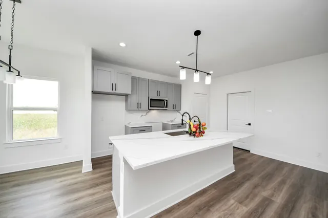 a view of a kitchen counter space a sink wooden floor and a window