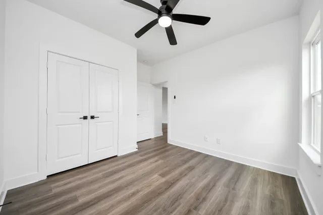 an empty room with wooden floor closet and windows