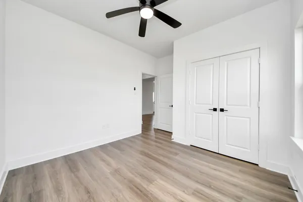 an empty room with wooden floor ceiling fan and windows