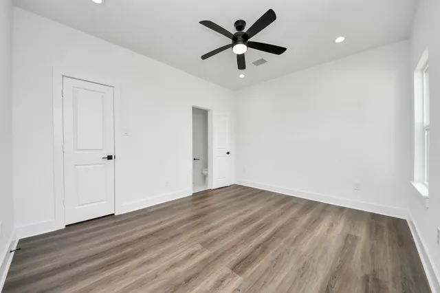 an empty room with wooden floor and windows