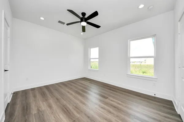 an empty room with wooden floor and windows