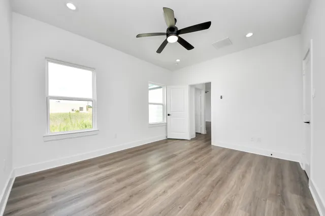 a view of empty room with wooden floor and fan