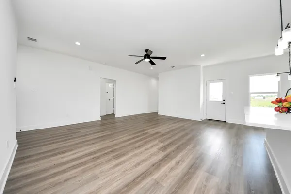 an empty room with wooden floor and ceiling fan