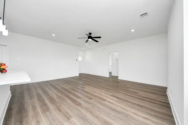 an empty room with wooden floor and ceiling fan