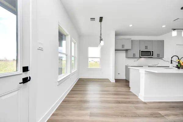 a view of a kitchen with a stove wooden cabinets and wooden floor