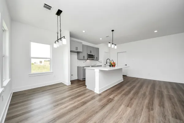 a view of a kitchen with kitchen island stainless steel appliances wooden floor and window