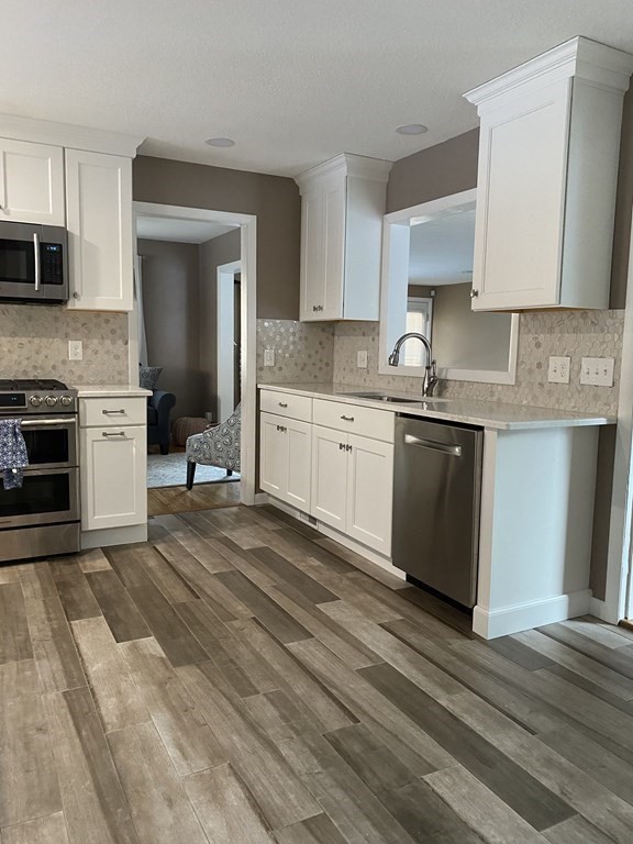 30 Hampton Knolls Road Holyoke, MA 01040 - Photo 9 of 38 a large kitchen with granite countertop a stove top oven a sink dishwasher and white cabinets with wooden floor
