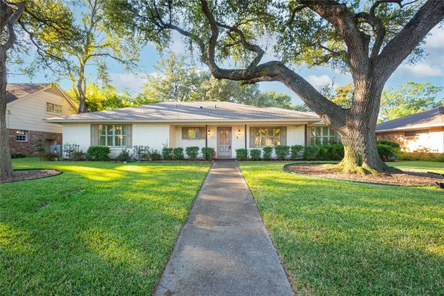 a view of house with a big yard and large trees