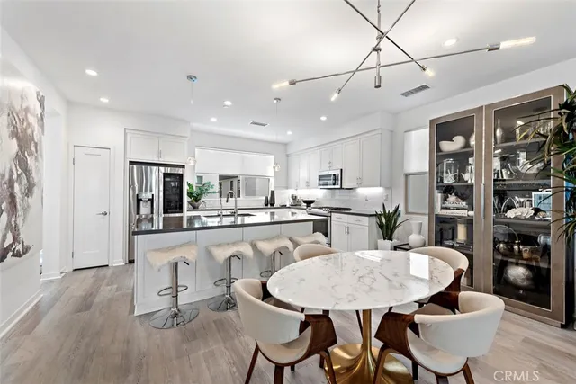 a kitchen with stainless steel appliances kitchen island granite countertop a dining table chairs and refrigerator