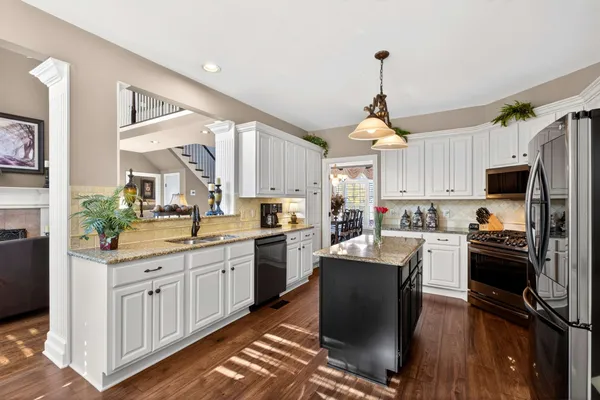 a kitchen with kitchen island granite countertop a sink cabinets stainless steel appliances and a window