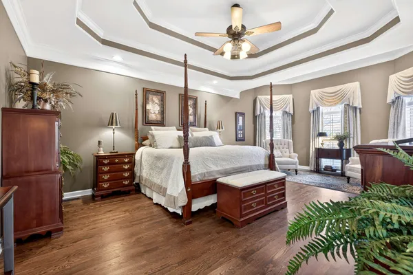a spacious bedroom with a large bed a chandelier and a dresser