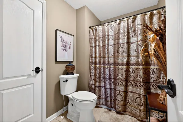 a bathroom with a toilet and a shower curtain