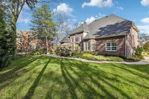 a view of a house with a big yard and large trees
