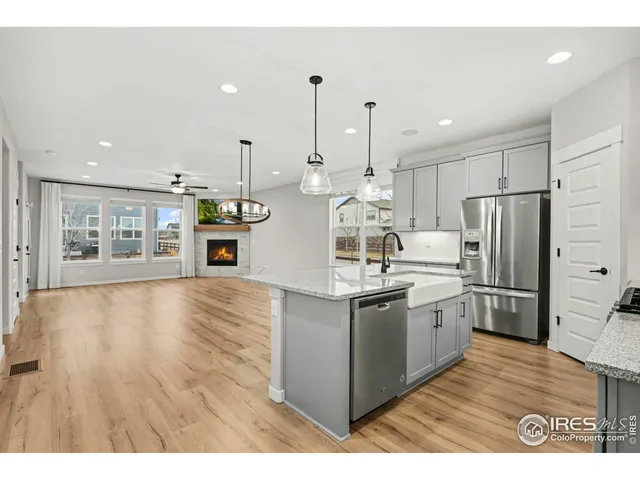 a kitchen with stainless steel appliances granite countertop a refrigerator a sink dishwasher a stove and a wooden floors