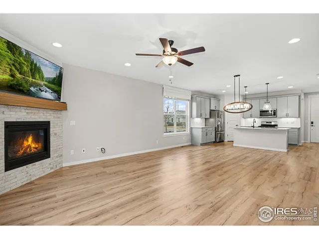 a view of an empty room and kitchen with fireplace wooden floor