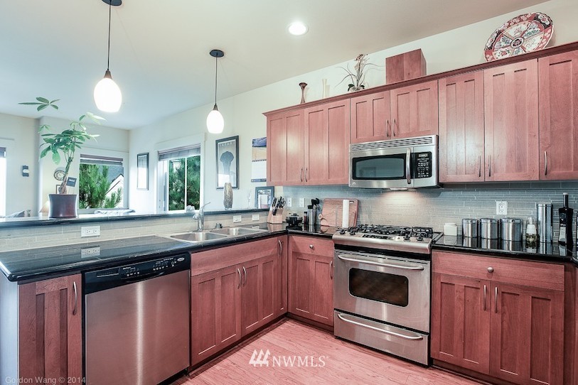 2115 201st Place Southeast, Unit F1 Bothell, WA 98012 - Photo 7 of 10 a kitchen with stainless steel appliances granite countertop a sink a stove a microwave and wooden cabinets