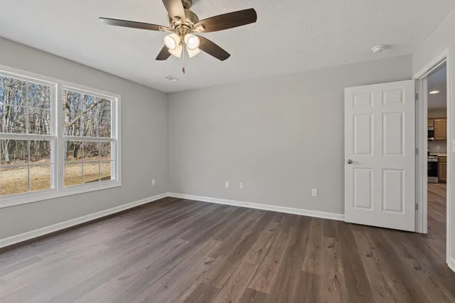 a view of an empty room with window and wooden floor