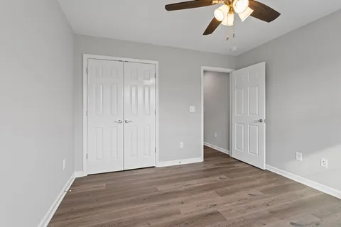 a view of a room with wooden floor and a chandelier fan