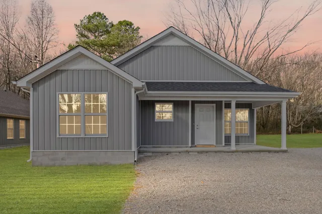 a view of a house with a yard and large tree