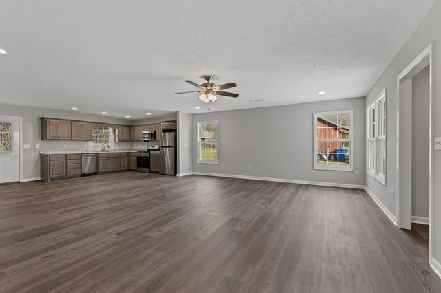 a view of kitchen with granite countertop stainless steel appliances cabinets and wooden floor