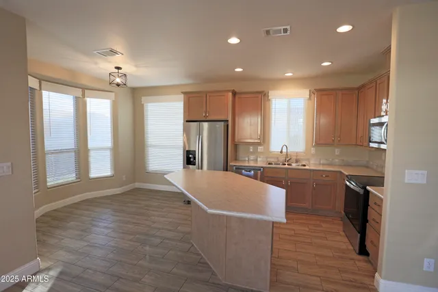 a large kitchen with kitchen island a large counter top space a sink stainless steel appliances and cabinets