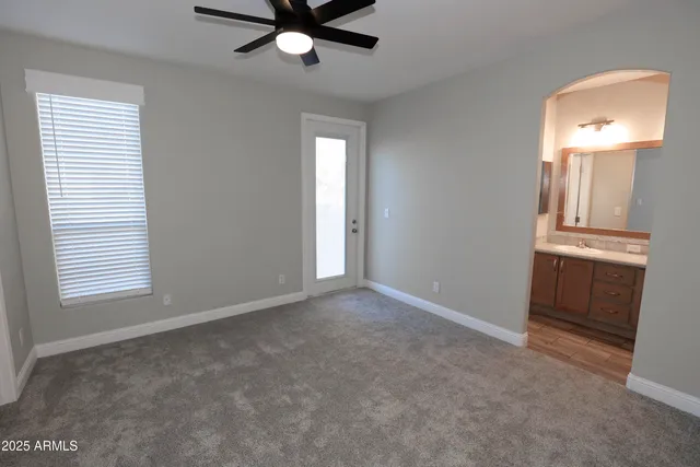 an empty room with a window and a chandelier fan