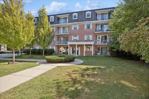 a view of a brick building next to a yard with big trees
