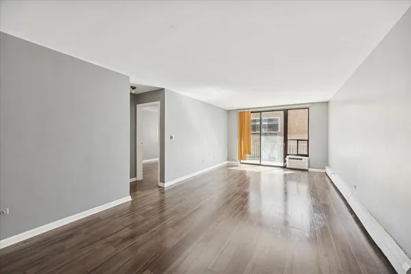 a view of an empty room with wooden floor and window