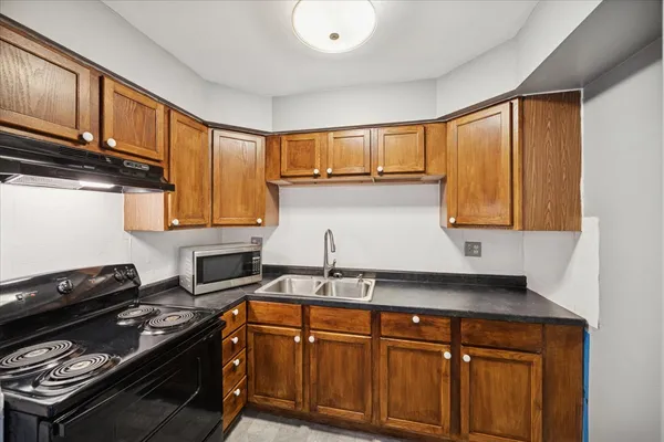 a kitchen with granite countertop a sink cabinets and stainless steel appliances