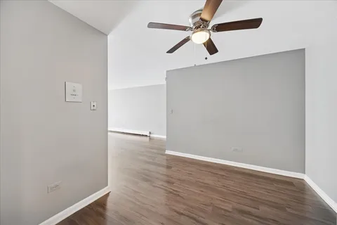 an empty room with wooden floor ceiling fan and window