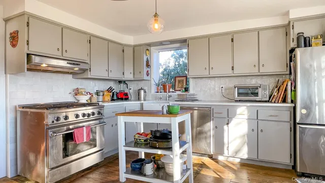 a kitchen with stainless steel appliances granite countertop a refrigerator a stove and white cabinets