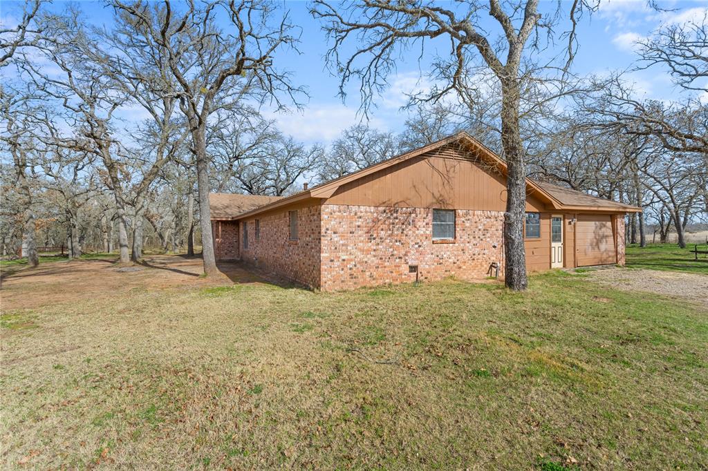 1447 Red Gate Road Mart, TX 76664 - Photo 17 of 38 a backyard of a house with large trees and garage