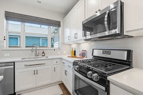 a kitchen with stainless steel appliances a sink dishwasher a stove and white cabinets